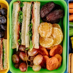 Colorful lunchbox filled with sandwiches, fresh fruits, and vegetables, perfect for a healthy meal.